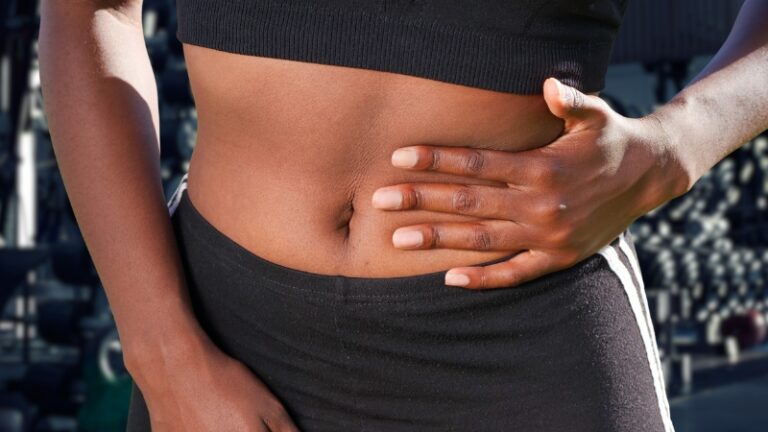 A woman holds her side in discomfort at the gym, showing stomach upset after exercising