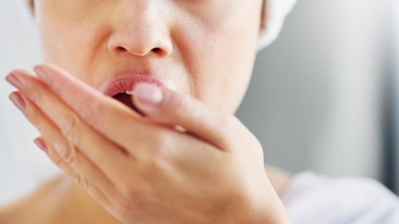 A woman covers her mouth while checking for bad breath