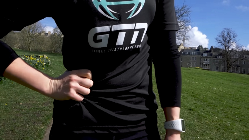 A person holds their side in discomfort outdoors after exercise