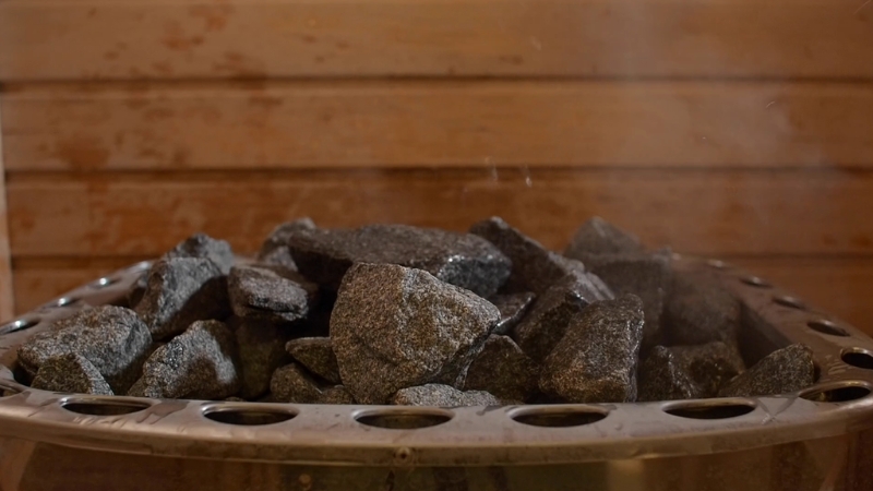 Hot sauna stones release heat and light steam inside a wooden room