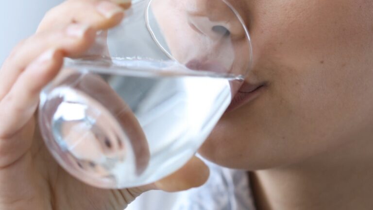 A person drinks a glass of water to show the start of the 30-Day Water Challenge
