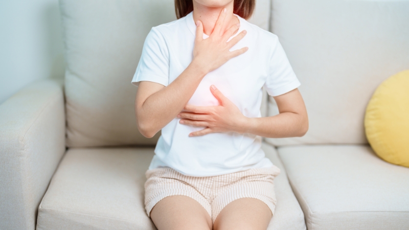 Person holds chest and throat in pain, showing acid reflux symptoms