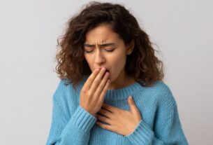 Person holding hand over mouth and chest appearing uneasy