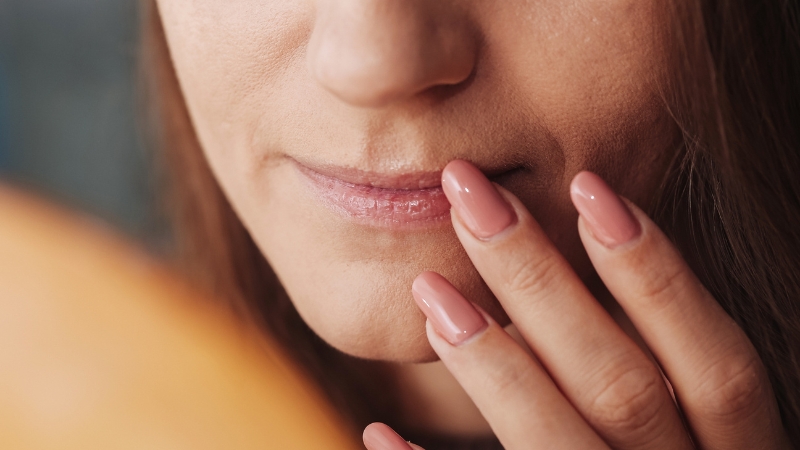 Person touching dry lips, showing relief efforts for dry mouth symptoms