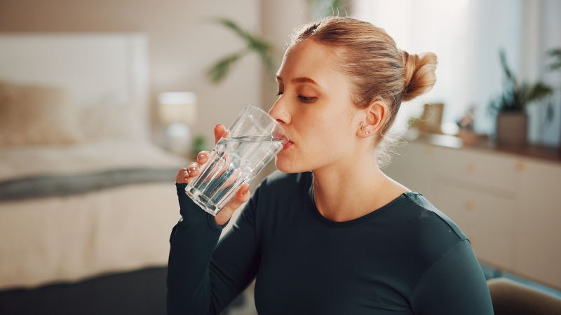 Woman drinking a glass of plain water indoors