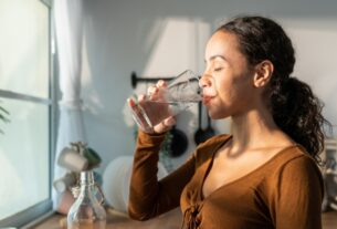 Woman drinking a glass of water at home in natural light