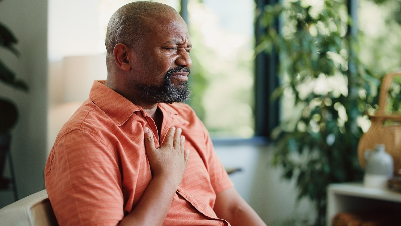 Man presses chest in discomfort, showing frequent acid reflux symptoms