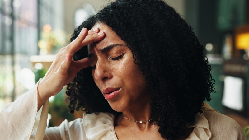 Woman holding her head with a pained expression, showing dehydration symptoms