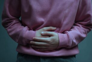 Close up of hands pressed against the abdomen showing stomach pain