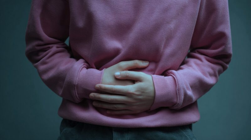 Close up of hands pressed against the abdomen showing stomach pain