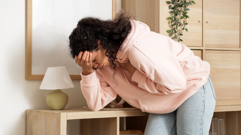 Woman leaning on table with hand on head during an anxiety spike