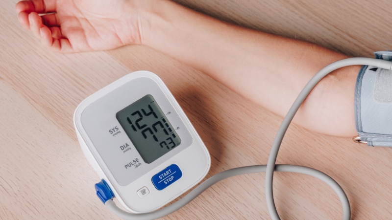 Digital blood pressure monitor on a table showing a 124/72 reading